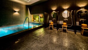 Um spa moderno com piscina, bancos de madeira e espelhos fixados na parede.