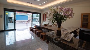 A modern reception area with a marble counter, a telephone, and a vase of flowers. - Place of Heart (Lugu)
