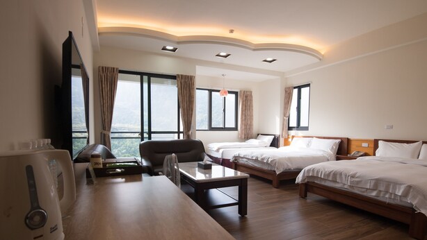 A hotel room with two beds, a desk with a kettle, a chair, and a TV. - Place of Heart (Lugu)
