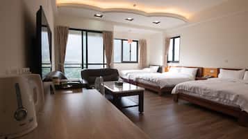 A hotel room with two beds, a desk with a kettle, a chair, and a TV.