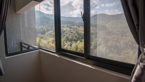 A room with a large window overlooking a forested mountain range. - Place of Heart (Lugu)