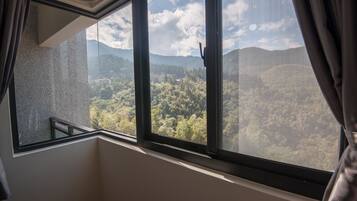 A room with a large window overlooking a forested mountain range.