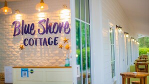 Placa para Blue Shore Cottage, com parede de tijolos e luminárias pendentes.