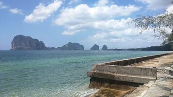 A coastal scene with a concrete walkway leading to the water, surrounded by rocky formations and clear skies.