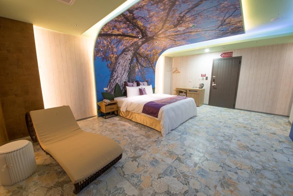 Quarto de hotel com uma cama grande, um chaise-longue, uma escrivaninha e um guarda-roupa.