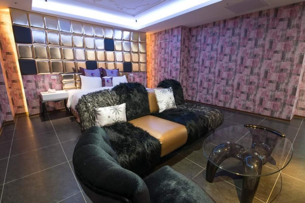 Een moderne hotelkamer met een comfortabele bank, een glazen bijzettafeltje en behang met een patroon.