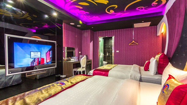 Een hotelkamer met twee bedden, een televisie, een bureau en een spiegel.