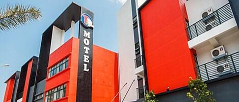 Un motel moderno con una fachada llamativa de color rojo y negro, que muestra un letrero que dice "Motel".