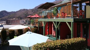 A restaurant with outdoor seating, red and white umbrellas, and a mountain backdrop. - La Posada (Fujikawaguchiko)