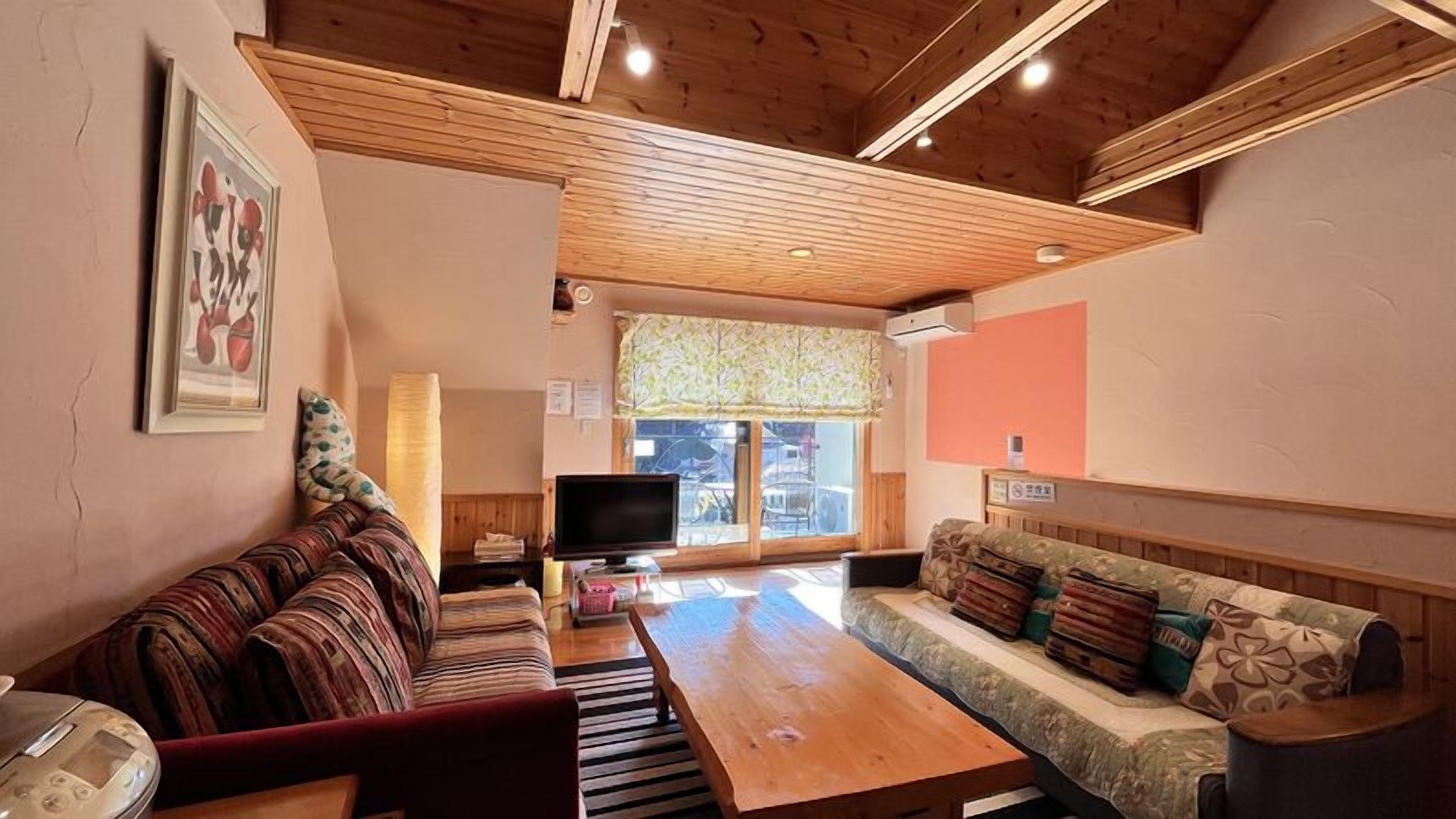 A living room with a sofa, a wooden coffee table, a television, and a window with a view.