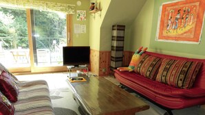 A living room with a striped sofa, a red sofa with patterned cushions, a wooden coffee table, and a television on a stand. - La Posada (Fujikawaguchiko)
