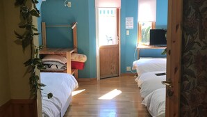 A bedroom with two beds, a wooden door, a window, and a wall-mounted air conditioner. - La Posada (Fujikawaguchiko)