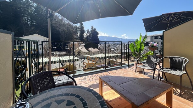 A patio area with outdoor furniture, a tiled table, and a view of a mountainous landscape. - La Posada (Fujikawaguchiko)