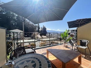 A patio area with outdoor furniture, a tiled table, and a view of a mountainous landscape. - La Posada (Fujikawaguchiko)