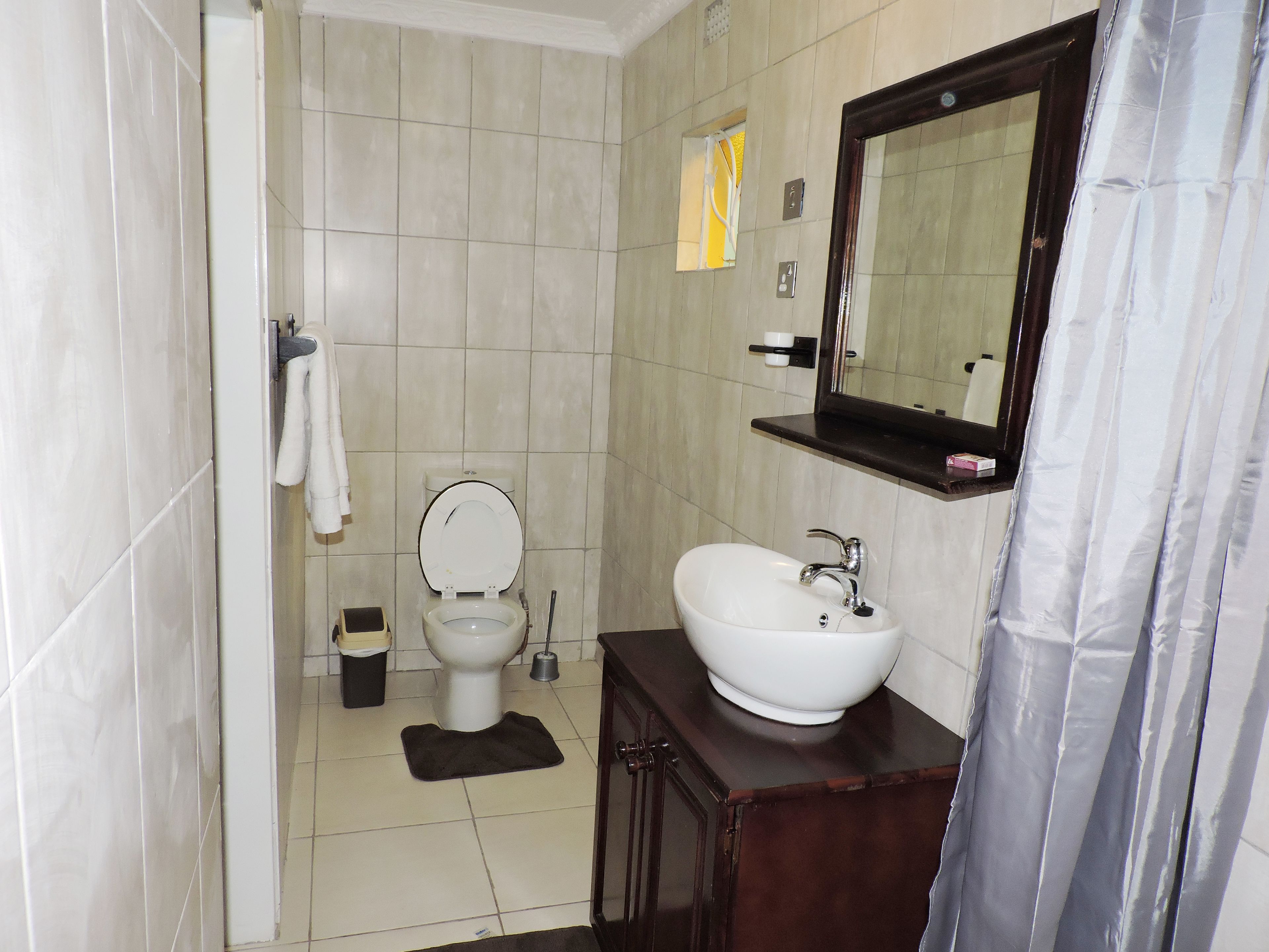 A bathroom with a toilet, sink, mirror, and tiled walls.