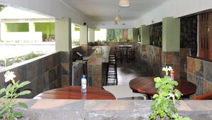 A restaurant with stone walls, wooden tables, and chairs. - Café Zambezi House of Africa - Hostel (Livingstone)