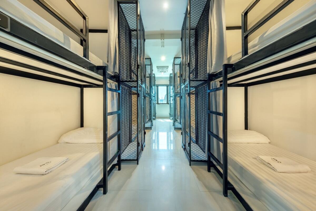 A corridor with bunk beds, metal railings, and a bright interior.