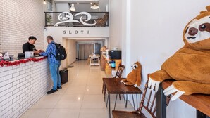 A reception area with a sloth-themed decor, including a sloth statue and plush sloth toys. - Sloth Hostel Don Mueang (Bangkok)