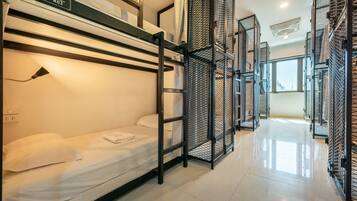 A modern hotel room with bunk beds, a metal partition, and a window providing natural light.
