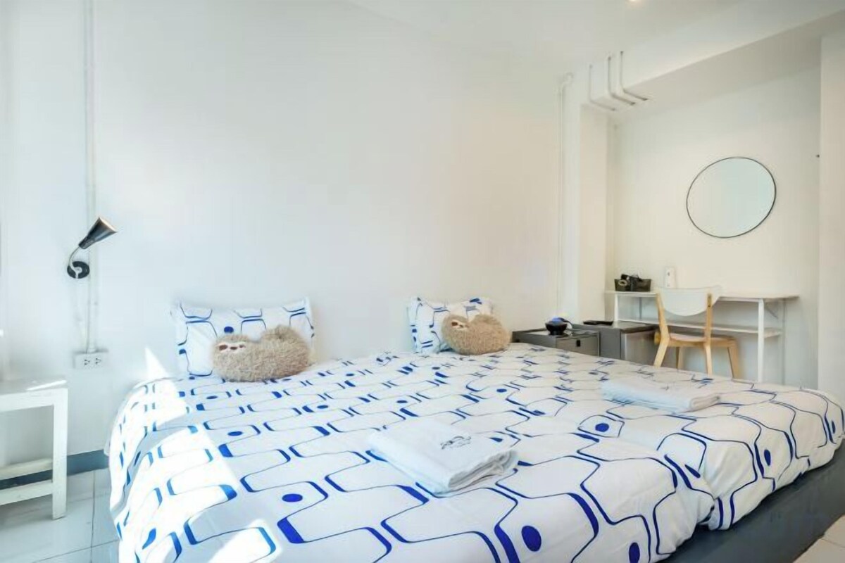 A modern bedroom with a large bed, a desk, and a chair.