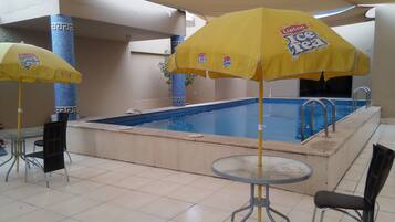 Una piscina al aire libre, sombrillas, sillones reclinables de piscina