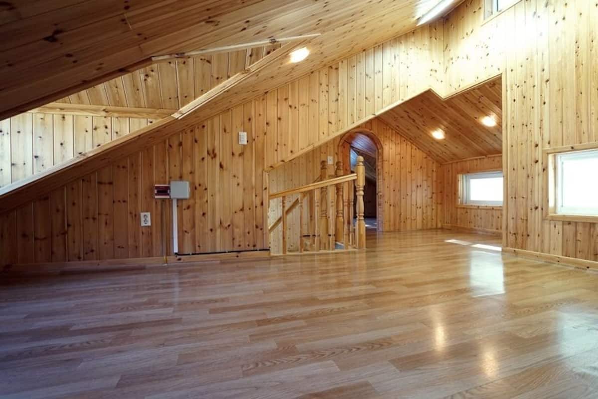 Un espacio amplio en el ático, con paredes de madera y techo inclinado.