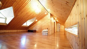 Una habitación amplia en el ático, con paredes de madera y techo inclinado.