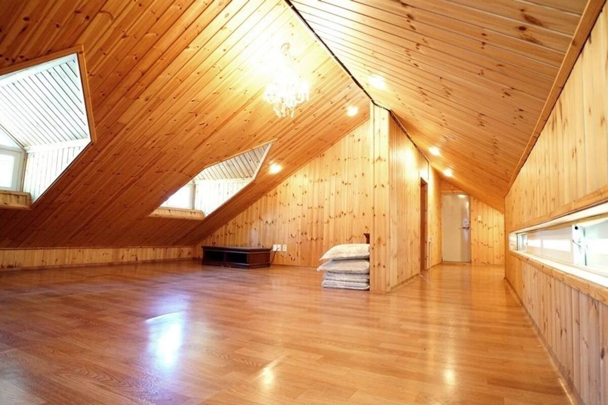 Una habitación amplia en el ático, con paredes de madera y techo inclinado.