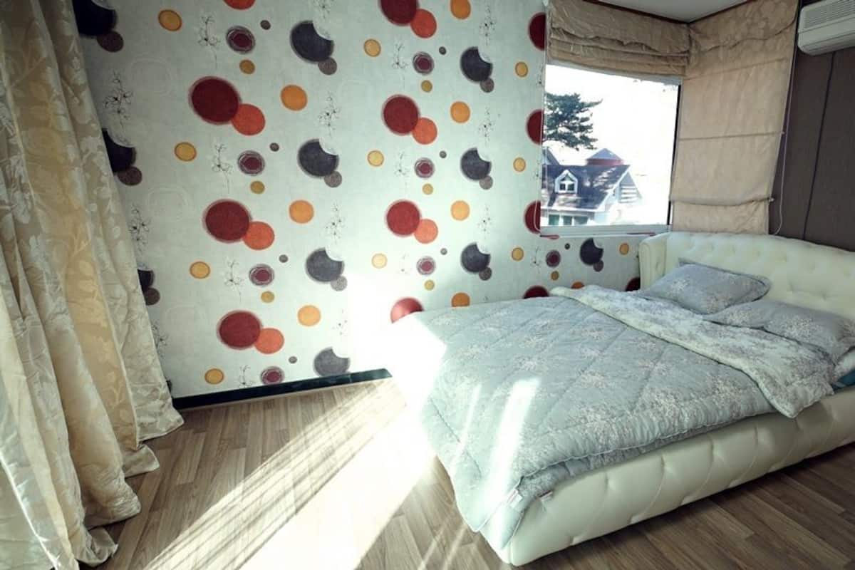 Un dormitorio con una cama, cortinas y una pared con estampado de lunares.