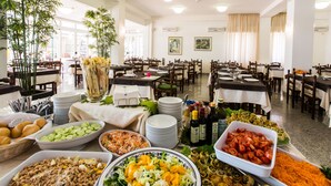 A buffet setup with various food items and dining tables. - Hotel Confort (Cattolica)