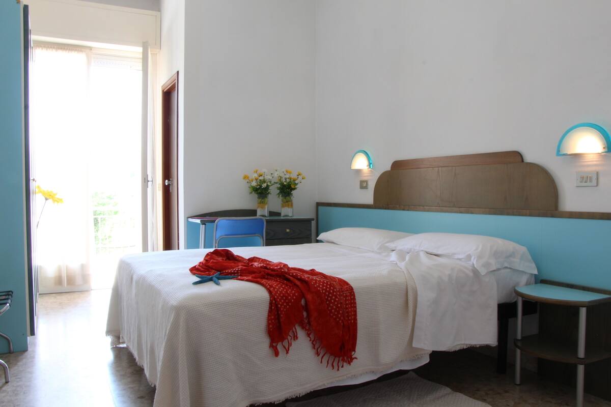 A bedroom with a bed, bedside tables, a desk, and a chair.