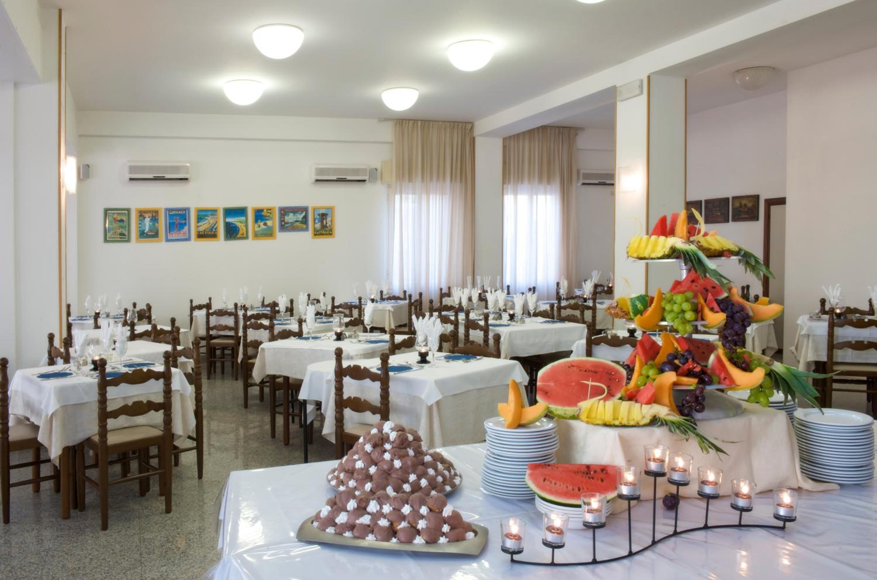 Comedor con varias mesas dispuestas para los comensales, con un centro de frutas y velas.