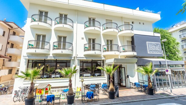 Un hotel con varios balcones, mobiliario exterior y plantas en macetas.