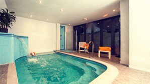 Una piscina interior con agua cristalina, un banco y una silla.
