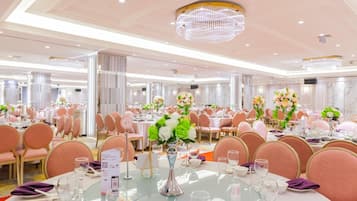A banquet hall with round tables, pink chairs, and floral centerpieces.
