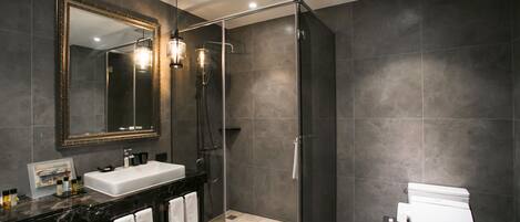 A modern bathroom with a glass-enclosed shower, a large mirror, and a white sink.