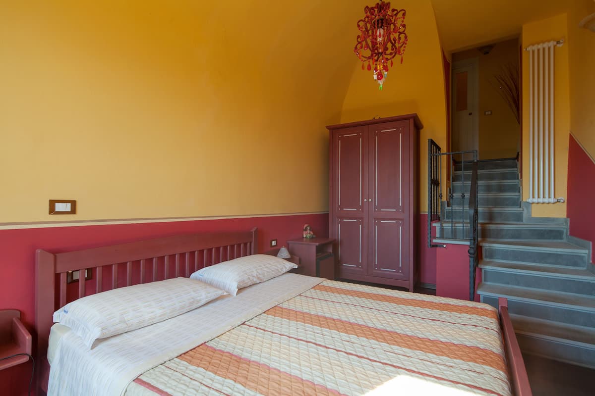 A bedroom with a bed, a wooden headboard, a nightstand, a wardrobe, and a staircase.