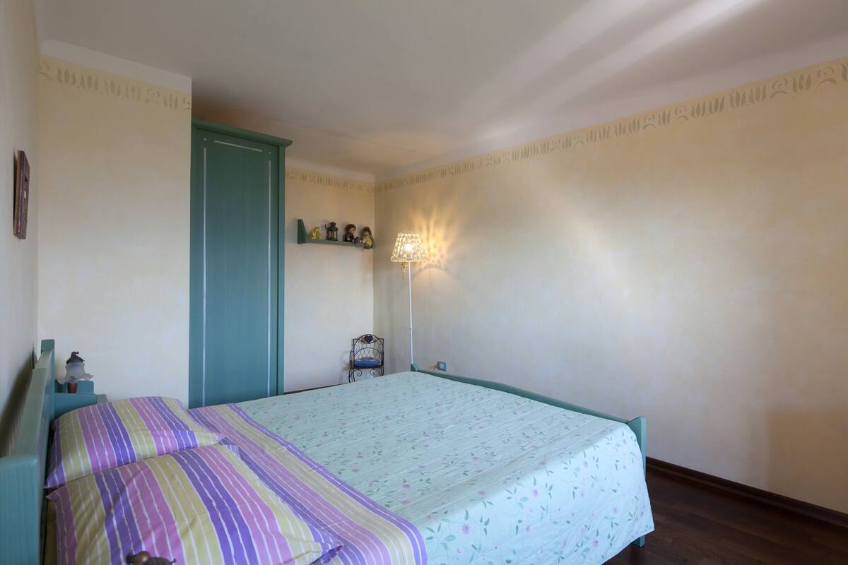 A bedroom with a bed, a nightstand, a lamp, and a door.