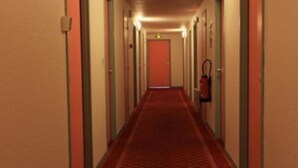 Un pasillo largo y estrecho con puertas a ambos lados y una alfombra roja.