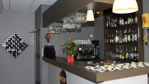Zona de bar con estanterías llenas de botellas, vasos y una barra con alimentos.