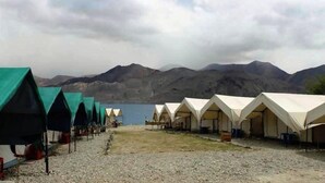 A row of tents with a lake and mountains in the background. - Wonderland Camps (Leh)