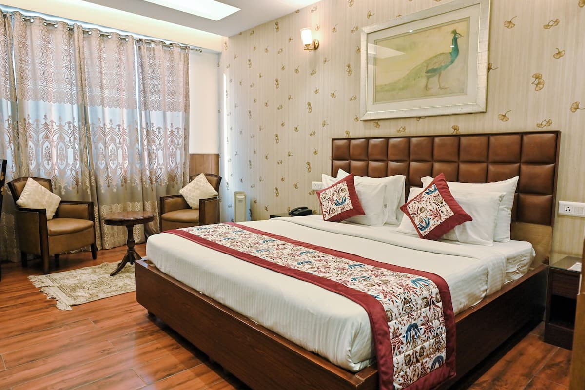 Une chambre d’hôtel avec un grand lit, deux chaises, une petite table et un tableau au mur.