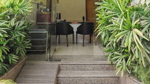 A hotel lobby with a staircase leading to a reception area. There are two black chairs and a small table in the center. - Imperial Apartments Gurugram (Gurugram)