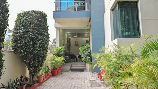 A modern building with a balcony, potted plants, and a staircase leading to the entrance. - Imperial Apartments Gurugram (Gurugram)