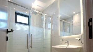 A modern bathroom with a glass-enclosed shower, a white toilet, and a sink with a marble countertop.
