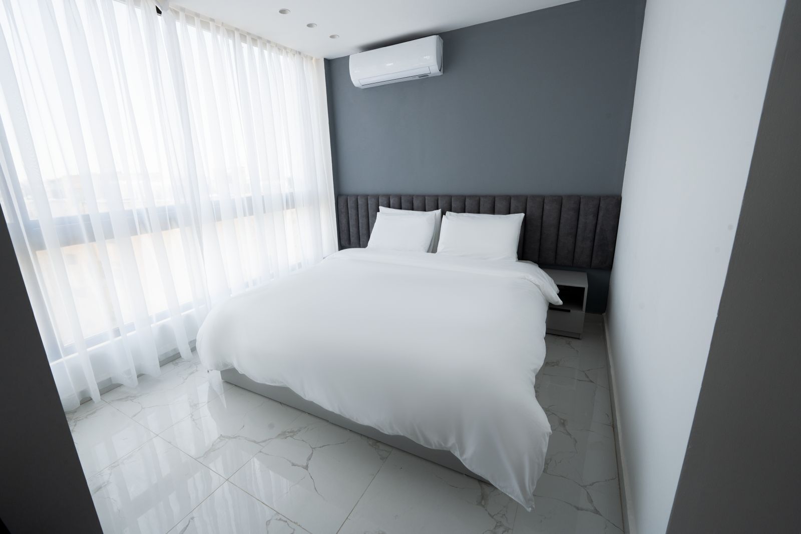 Une chambre d’hôtel moderne dotée d’un grand lit, d’une table de chevet et d’un système de climatisation intégré.