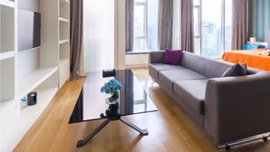 Ett modernt vardagsrum med en soffa, ett soffbord och en tv som står på en hylla.