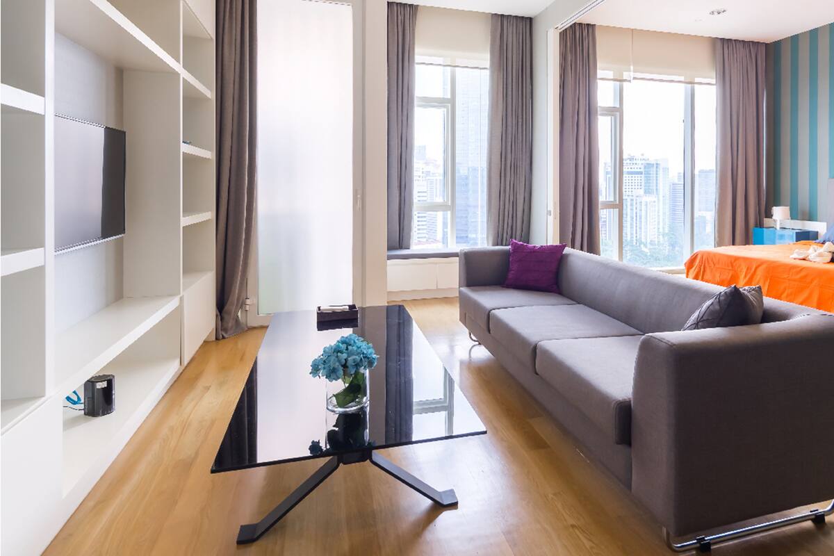 A modern living room with a sofa, a coffee table, and a TV on a shelf.