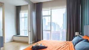 Ett modernt hotellrum med en stor säng, utsikt över staden och ett fönster med gardiner.
