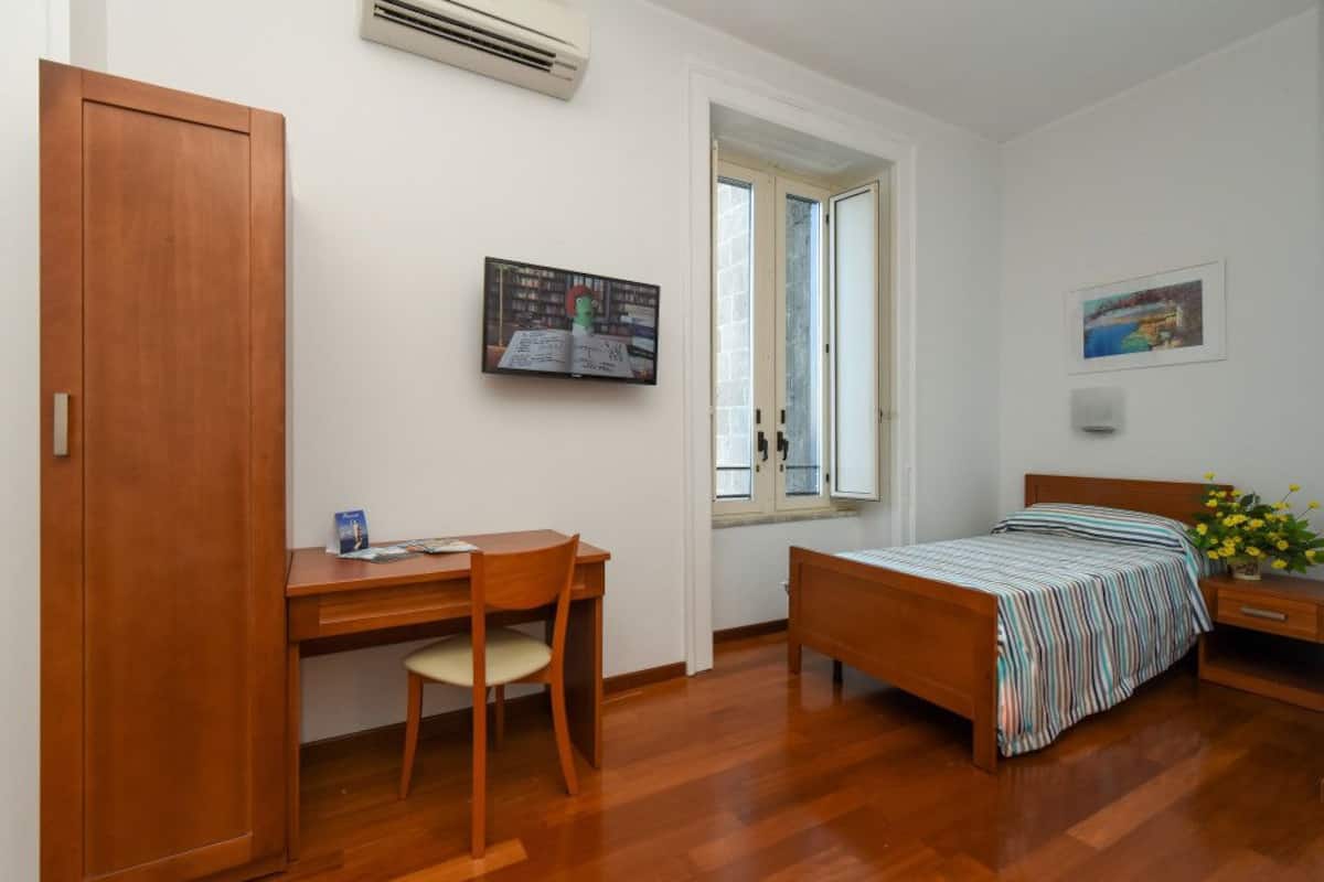 A bedroom with a wooden desk, chair, and bed.